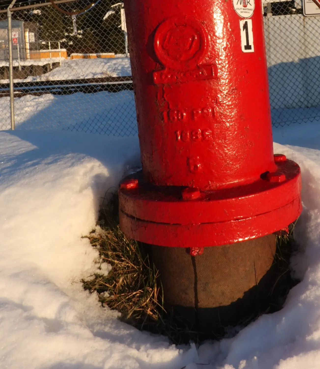 A red fire hydrant standing in deep snow, its pressure rating cast into the iron